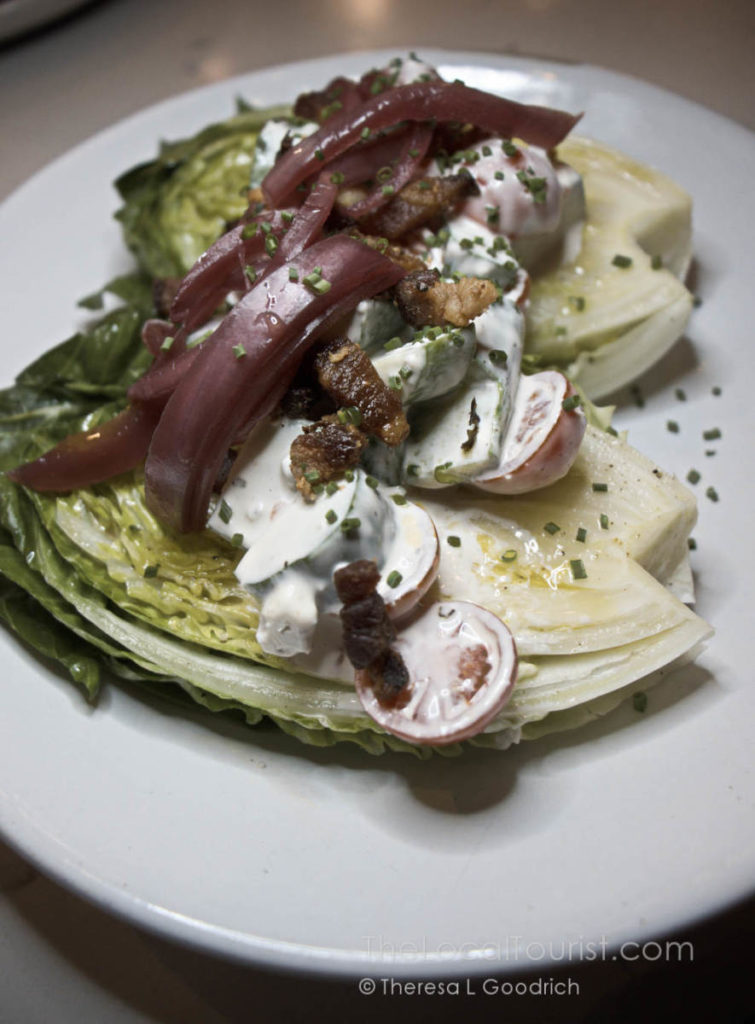 Iceberg gems - twist on the wedge salad topped with red onions, cucumbers, tomatoes, bacon, and bleu cheese dressing